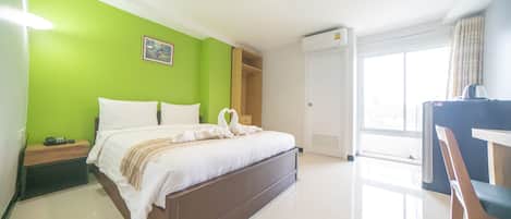 A hotel room with a bed, a desk, a chair, a wardrobe, and a window.
