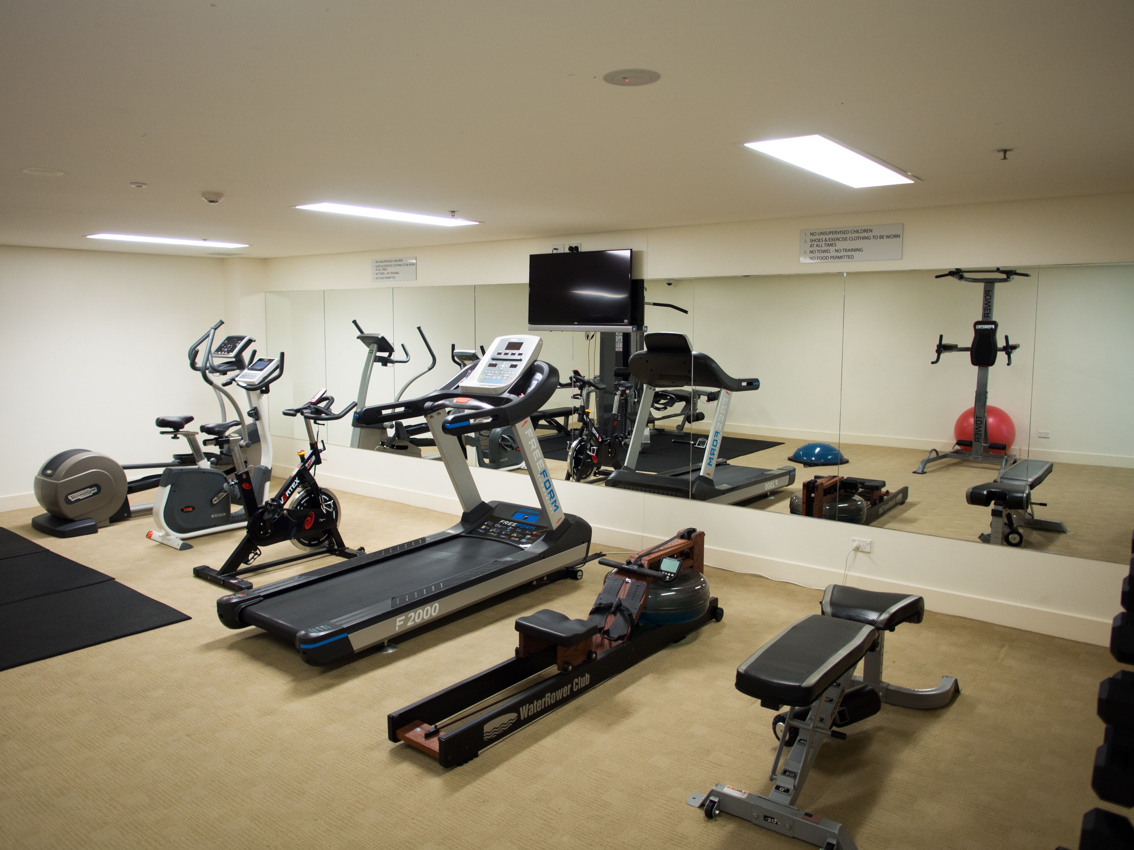 A gym with various exercise equipment including treadmills, stationary bikes, and weight machines.