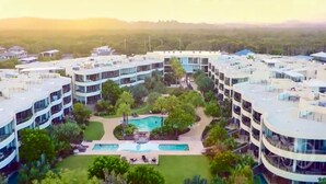 Un hotel moderno de varios pisos con un patio central que cuenta con una piscina y zonas de descanso.