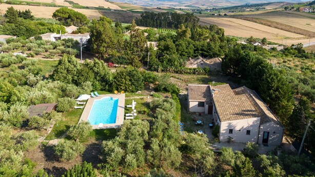 A villa with a swimming pool, surrounded by lush greenery and a view of distant hills and wind turbines. - Beautiful private villa for 14 people with WIFI, private pool, TV, terrace and pets allowed (Buseto Palizzolo)
