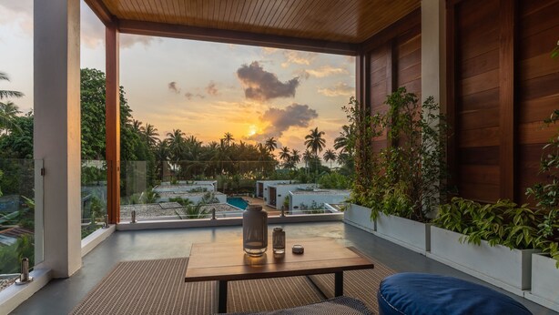 A modern room with a large window, a wooden ceiling, and a view of palm trees and a sunset. - Zee Luxury Boutique Hotel (Ko Pha-ngan)