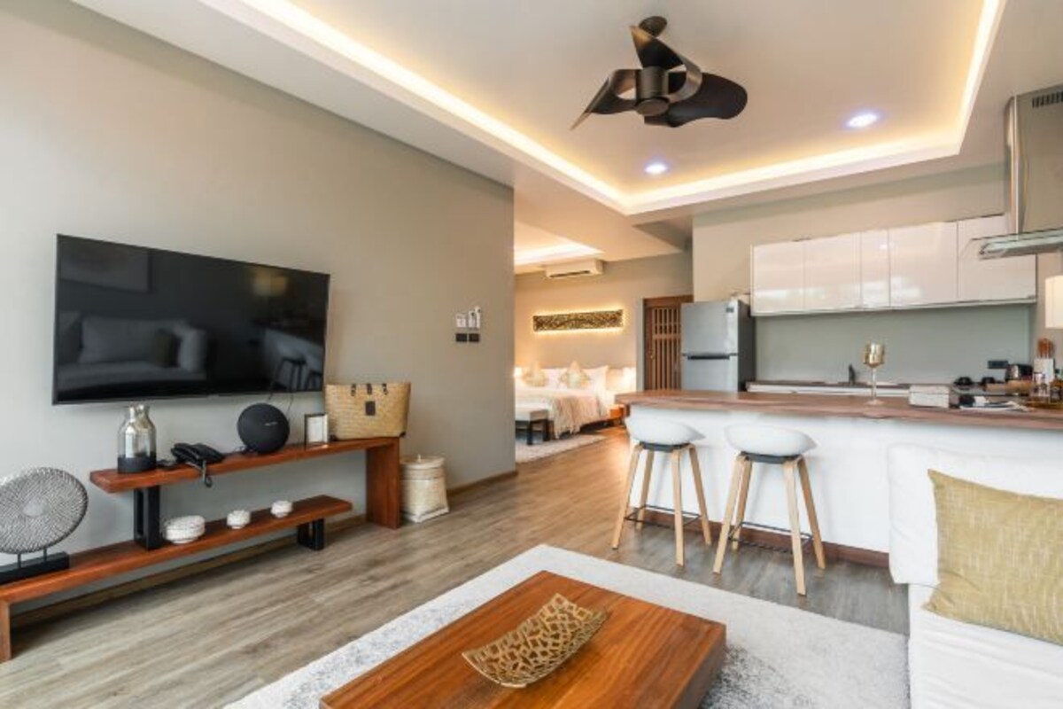 A modern living room with a flat-screen TV, wooden entertainment unit, and a cozy seating area with a coffee table.