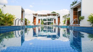 A modern pool area with clear blue water, surrounded by white walls and wooden accents, featuring a central glass door entrance. - Zee Luxury Boutique Hotel (Ko Pha-ngan)