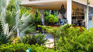 A restaurant with a white exterior, surrounded by lush greenery and hanging decorative lights. - Zee Luxury Boutique Hotel (Ko Pha-ngan)