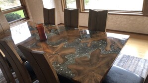 A dining table with a unique wood and stone design, surrounded by chairs. - One block to the beach, beautiful 3bd/3ba house with view, come relax and enjoy (Warrenton)