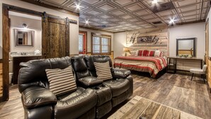 Una habitación con un sofá de cuero, una cama con ropa de cama roja y blanca, una pared de madera con un espejo y un techo con diseño geométrico.