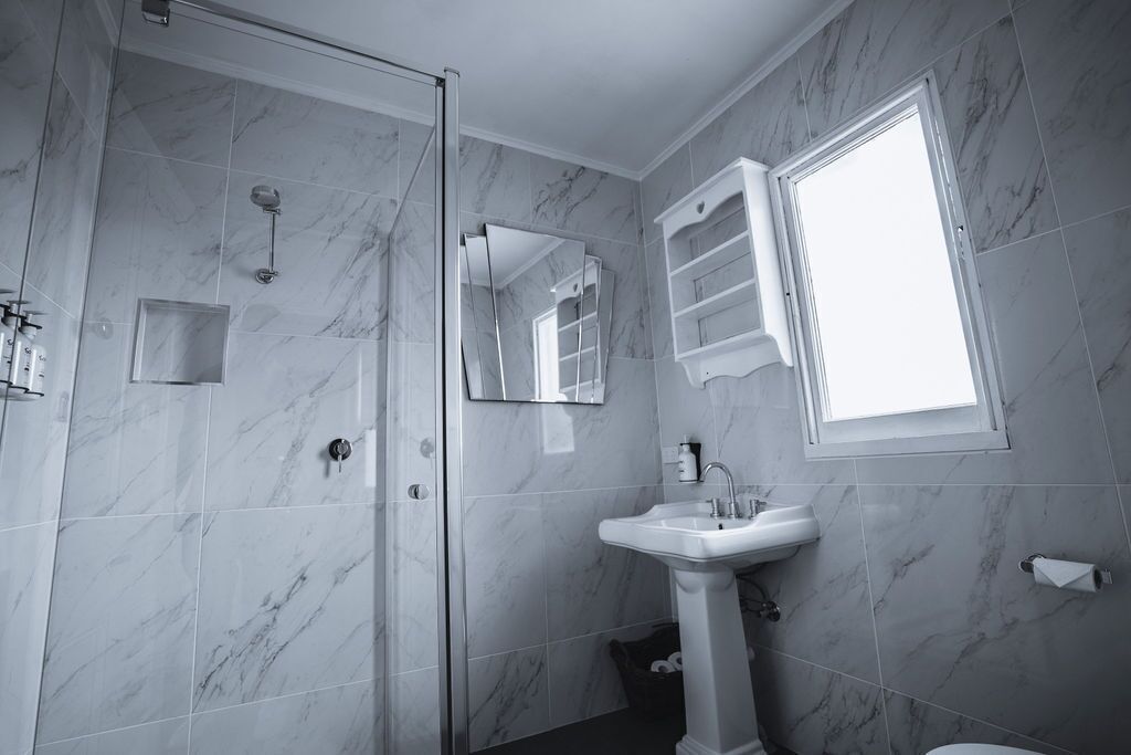 A bathroom with a shower, a sink, a mirror, and a window.
