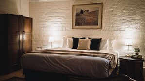 Un dormitorio con una cama grande, dos lámparas de noche, un cuadro enmarcado en la pared y un armario de madera.