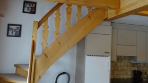 A wooden staircase leading to a second floor, a white refrigerator, and a kitchen area with a tiled backsplash. - Apartment Reseda by Interhome (Lenk)