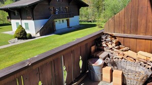 A wooden chalet with a balcony, a pile of firewood, and a metal bucket. - Apartment Reseda by Interhome (Lenk)
