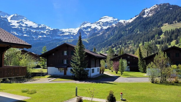 A row of chalet-style buildings with a mountain backdrop. - Apartment Reseda by Interhome (Lenk)
