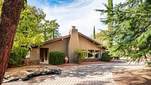 A house with a brick driveway, a chimney, and a well-maintained garden. - Rooftop Deck, Sedona Views, Fenced Yard +Pets! (Sedona)