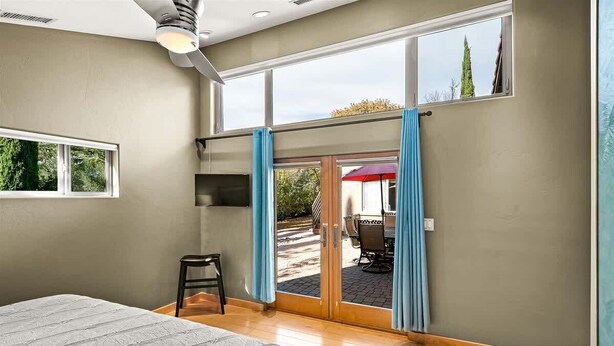 A bedroom with a bed, a chair, a TV, and a sliding glass door leading to an outdoor area with a table and umbrella. - Rooftop Deck, Sedona Views, Fenced Yard +Pets! (Sedona)