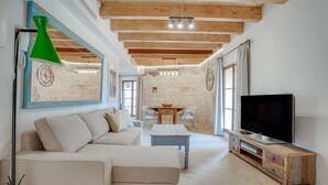 A living room with a sofa, TV, wooden beams, and a dining area. - VINTAGE PALMA PALACE (SUPERIOR 4) by Priority (Palma de Mallorca)