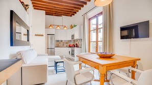 A modern kitchen with a refrigerator, microwave, and stove. There is a dining table with chairs and a bowl on it. - VINTAGE PALMA PALACE (SUPERIOR 5) by Priority (Palma de Mallorca)