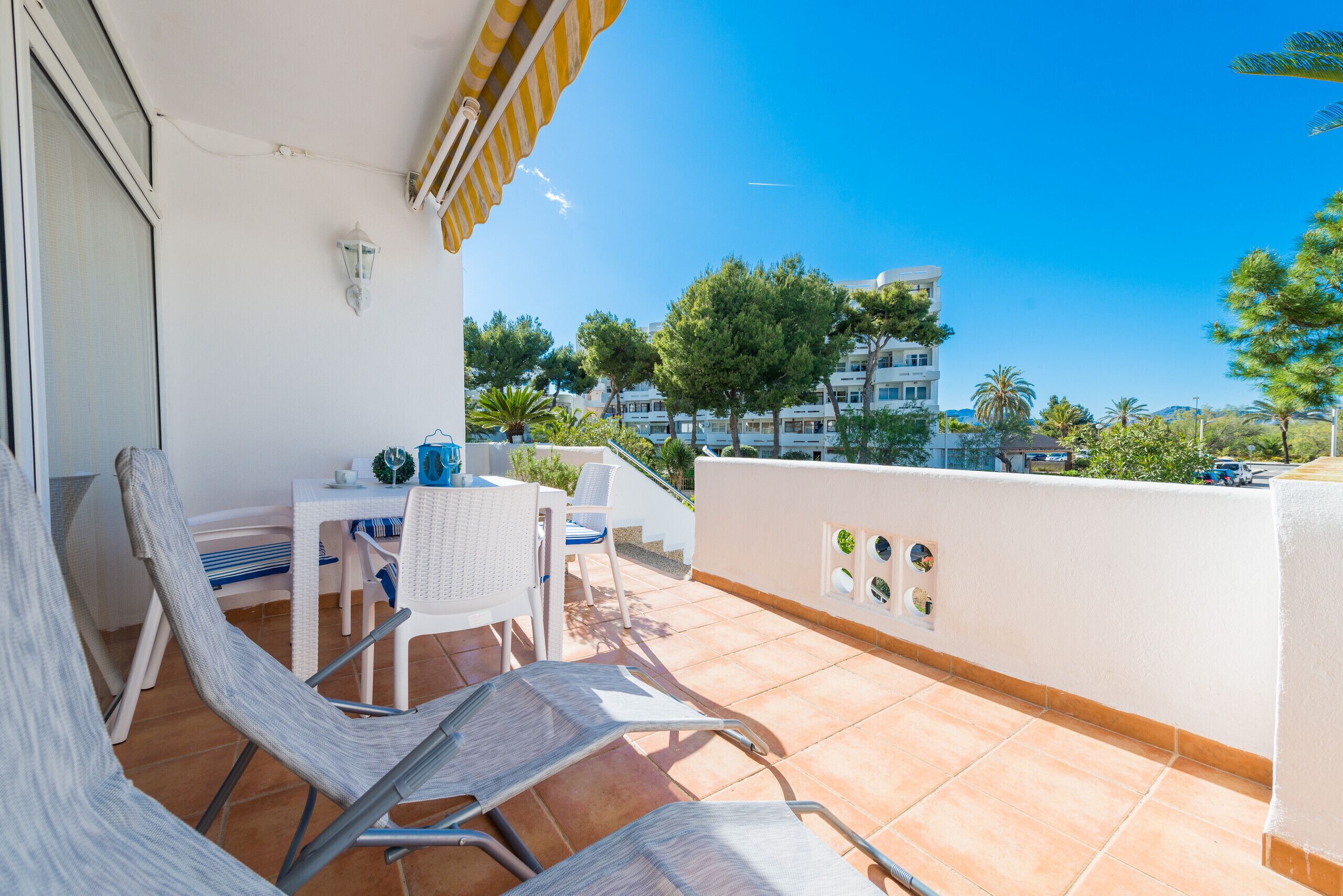 Ein Balkon mit Tisch und Stühlen, Blick auf die umliegenden Gebäude und einem klaren Himmel.