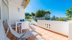 Un balcon avec une table et des chaises, une vue sur les bâtiments environnants et un ciel dégagé.