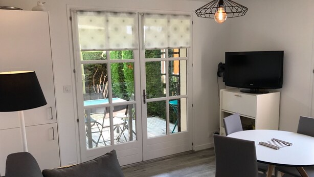 Un salon moderne avec un téléviseur, une table à manger et un canapé.