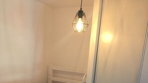Un lit superposé avec un matelas à motifs, une tête de lit blanche et une suspension lumineuse.