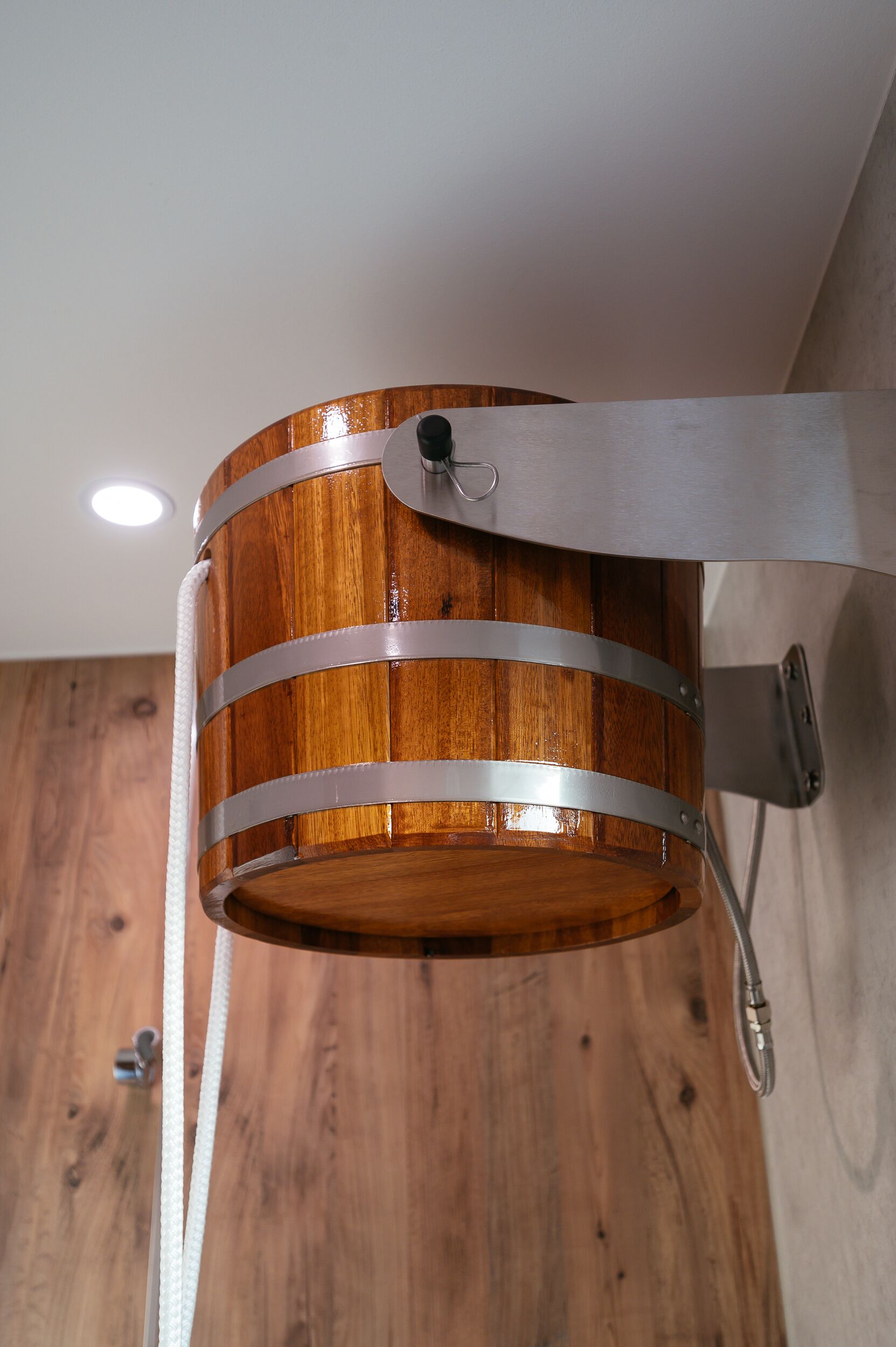 Eine wandmontierte Leuchte in Form eines Holzfasses, befestigt mit einer Metallhalterung.