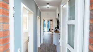 A hallway with a wooden floor, white walls, and a brick accent wall.