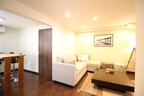 A living room with a sofa, a coffee table, a dining table with chairs, and a framed picture on the wall. - Xiaoningge (Osaka)