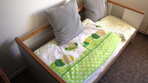 A single bed with a wooden frame, two pillows, and a green polka dot bedspread. - Apartment 2 - Apartment Rosenstadt (Forst (Lausitz))