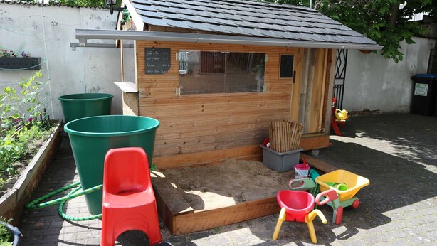 A wooden playhouse with a small window, surrounded by a sandbox and a slide. - Apartment 2 - Apartment Rosenstadt (Forst (Lausitz))
