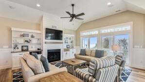 A spacious living room with a fireplace, comfortable seating, and a large window providing a view of the outdoors.