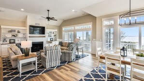 A spacious living room with a fireplace, a television, and a dining area with a view of the outdoors.