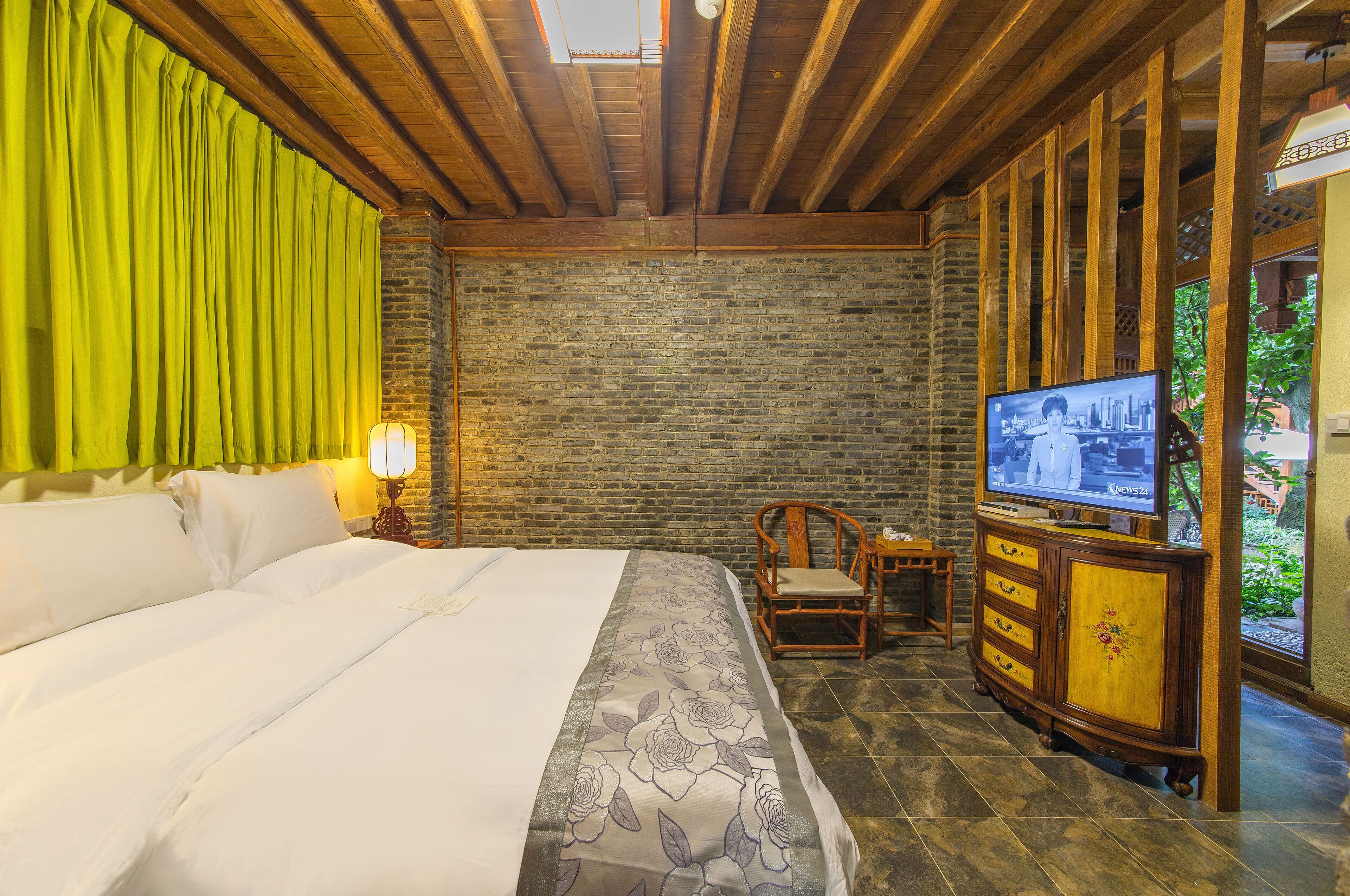 Una habitación de hotel con una cama grande, un mueble de madera con un televisor y una pared de ladrillo.