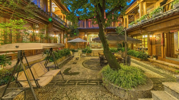 En innergård med traditionell arkitektur, sittplatser och krukväxter.