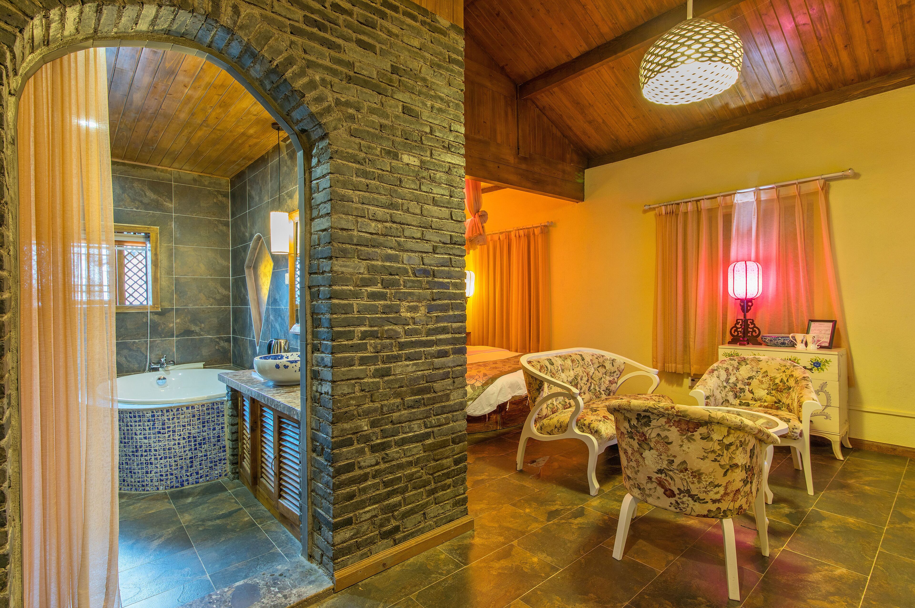 Une salle de bain avec une baignoire et une douche, un plafond en bois et un mur en briques.