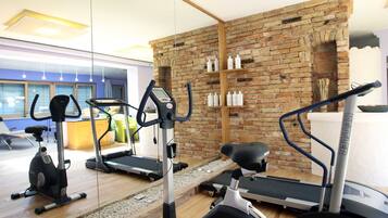 A gym with exercise equipment, a brick wall, and a wooden floor.