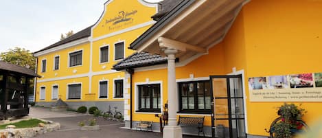 A yellow building with a sign reading 'Petersdorf Hotel.' There are benches outside, a bicycle, and a dog in the foreground.