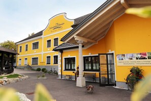 Een geel gebouw met een bord waarop 'Petersdorf Hotel' staat. Voor de gevel staan bankjes, een fiets en een hond op de voorgrond.