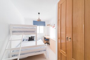 A bedroom with a bunk bed, a desk, and a wardrobe.