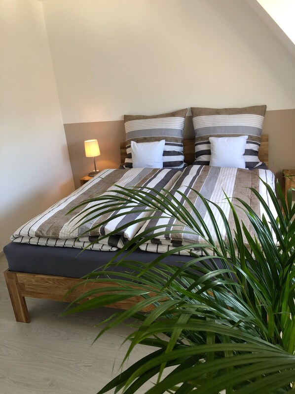 A neatly made bed with striped bedding and a wooden headboard.