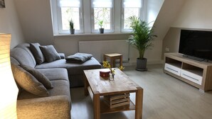 A modern living room with a grey sofa, wooden coffee table, and a TV stand.