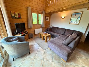 Ein gemütliches Wohnzimmer mit einer Couch, einem Sessel und einem Fernseher.