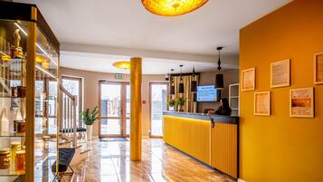 Een hotel lobby met een receptiebalie, een glazen vitrine, een trap en een groot raam.
