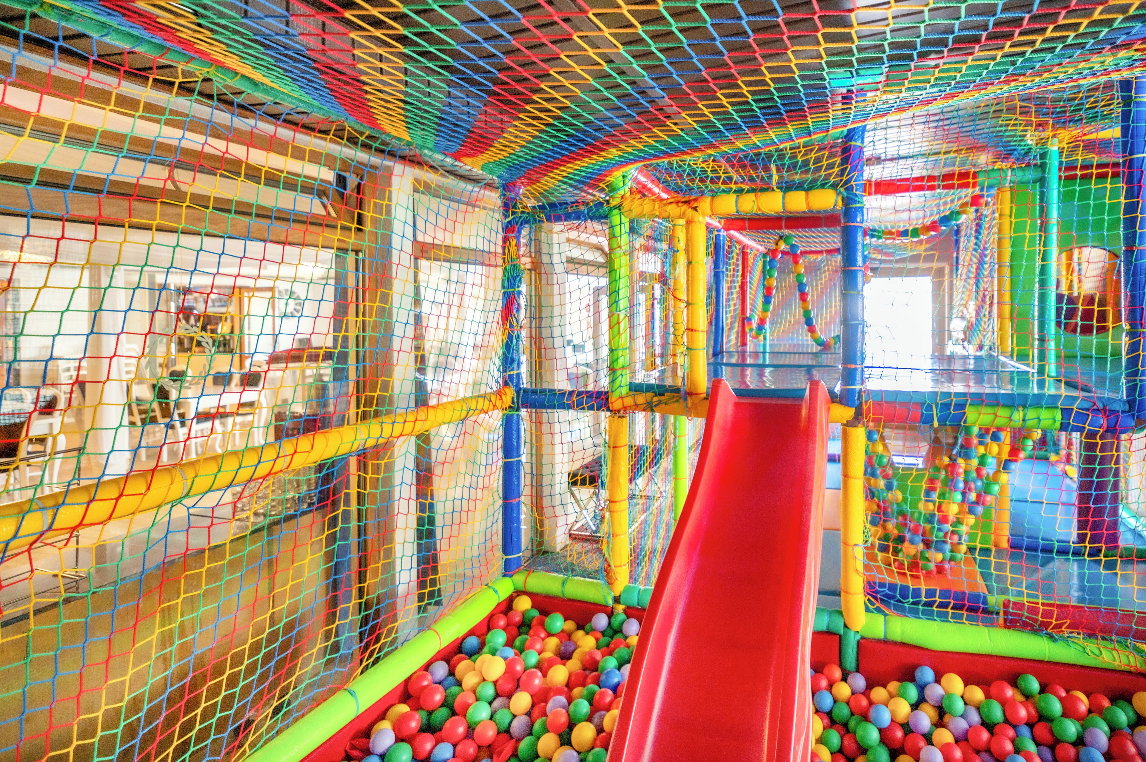A colorful indoor play area with a red slide and a ball pit.