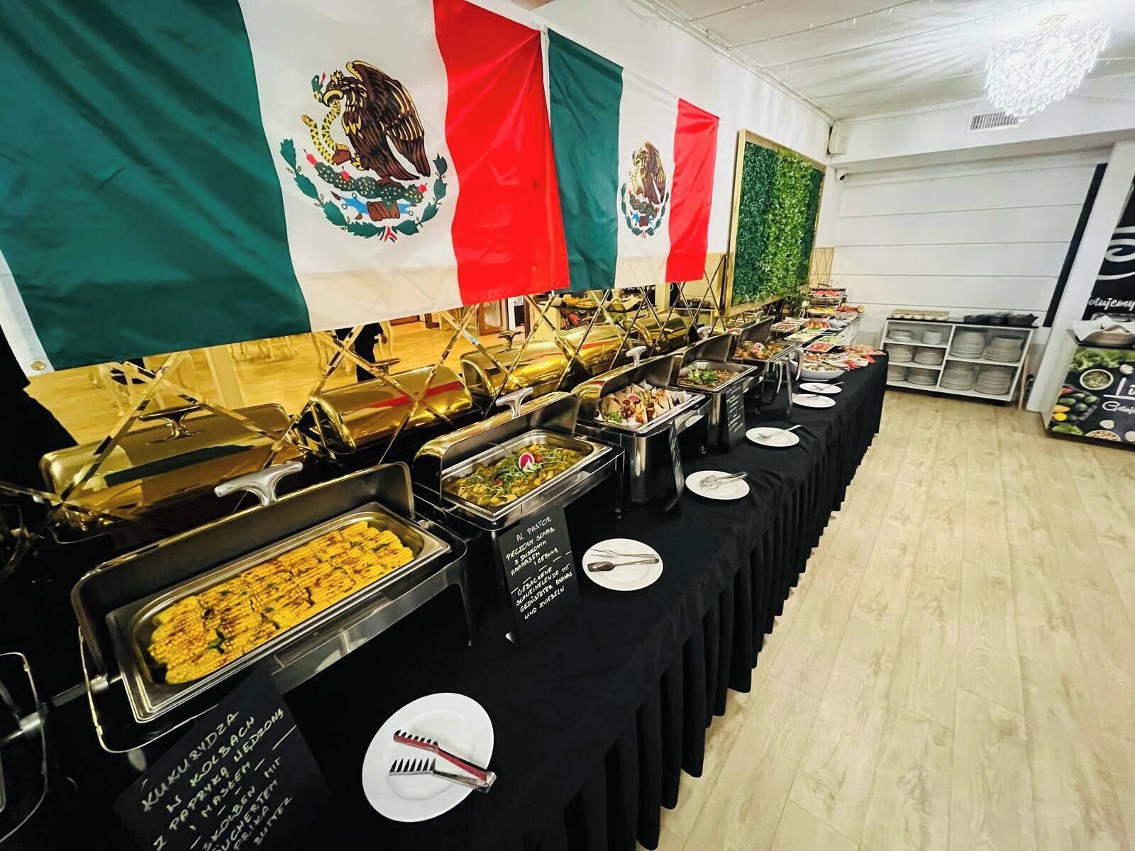 A buffet setup with multiple food stations and Mexican flags in the background.