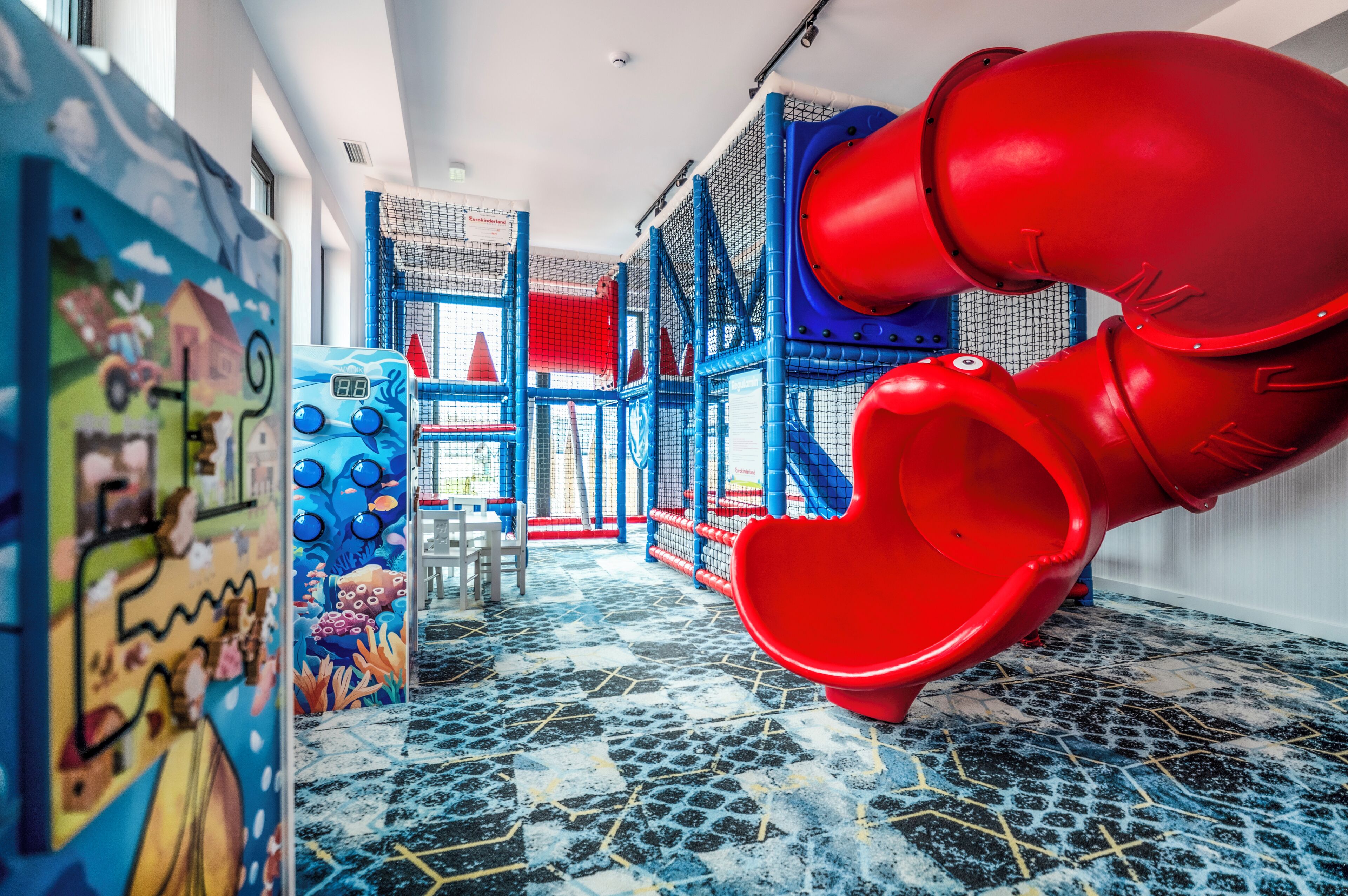 Uma área de recreação infantil com escorrega, estruturas de brincar e um mural.