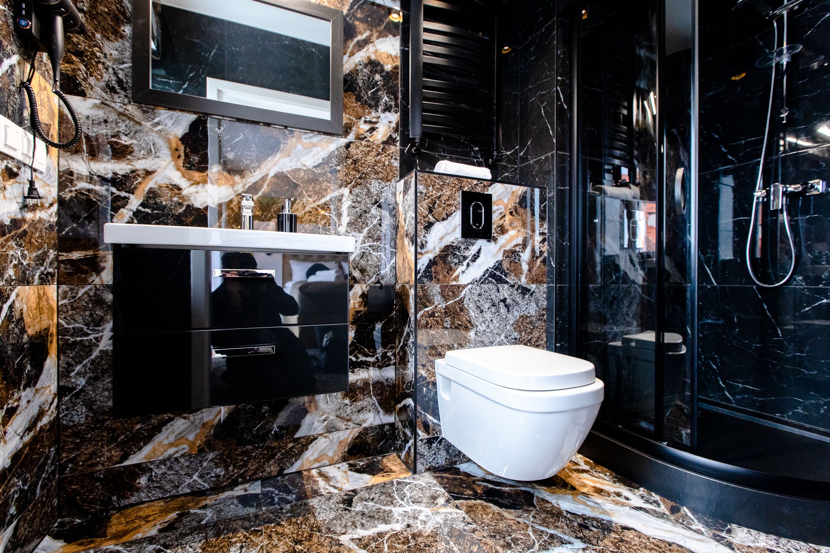Un baño moderno con salpicadero de mármol, inodoro blanco, cabina de ducha de vidrio y espejo montado.
