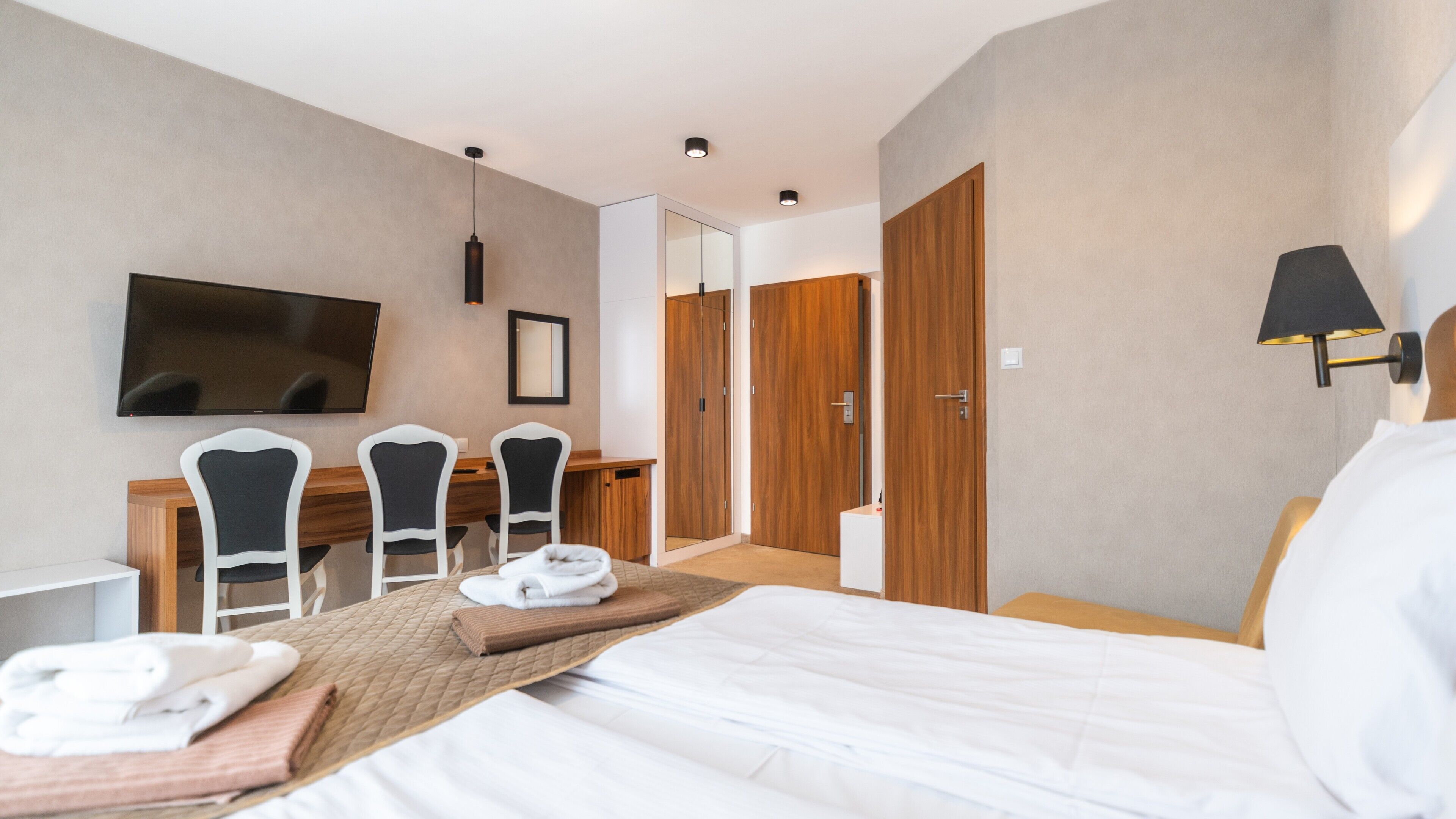 Ein Hotelzimmer mit einem Bett, einem Schreibtisch mit Stühlen, einem Fernseher und einem Kleiderschrank.