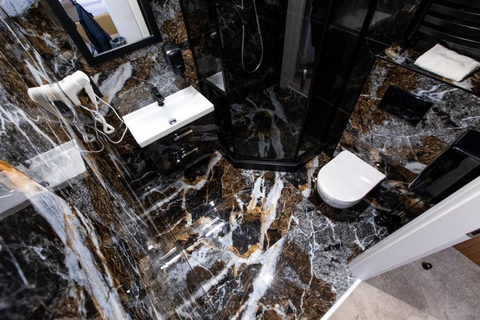Une salle de bain avec un sol en marbre, un lavabo blanc, des toilettes et un espace douche.
