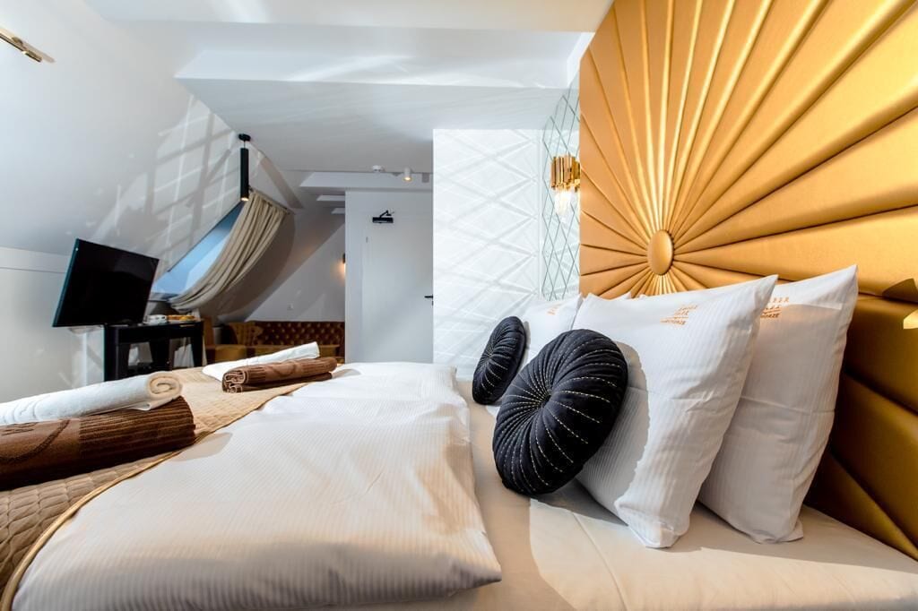 Una camera d'albergo moderna con un letto grande, una televisione e una testiera unica a forma di raggio di sole.