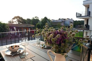 Un balcone con un tavolo apparecchiato per mangiare, con un vaso di fiori e una ciotola.