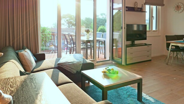 Una sala de estar moderna con un sofá, una mesa de centro, un televisor y un comedor con una mesa y sillas.